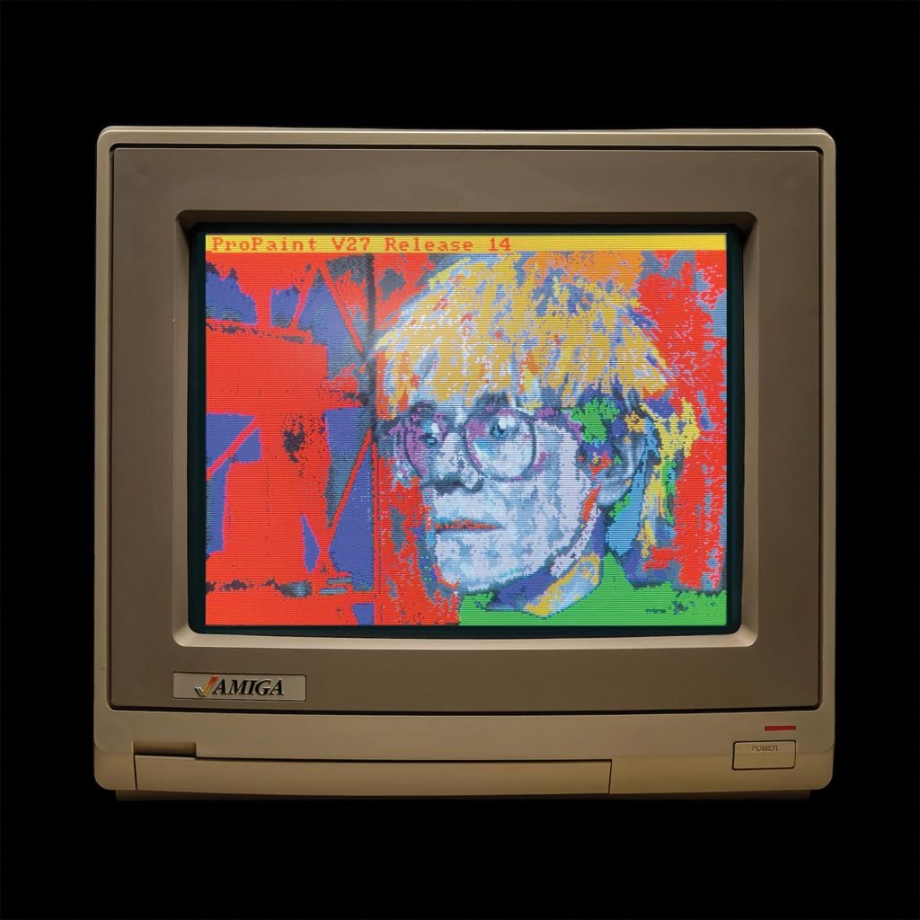 A pixelated Warhol self portrait created with a computer and shown on an Amiga monitor