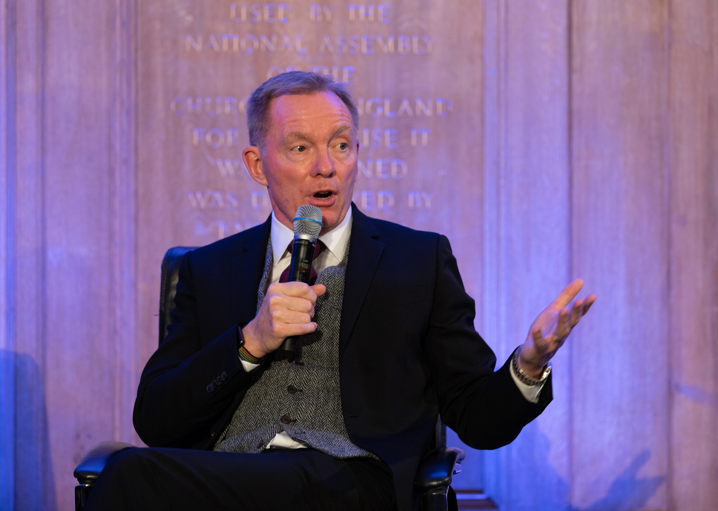 a man in a suit speaks into a microphone on a stage