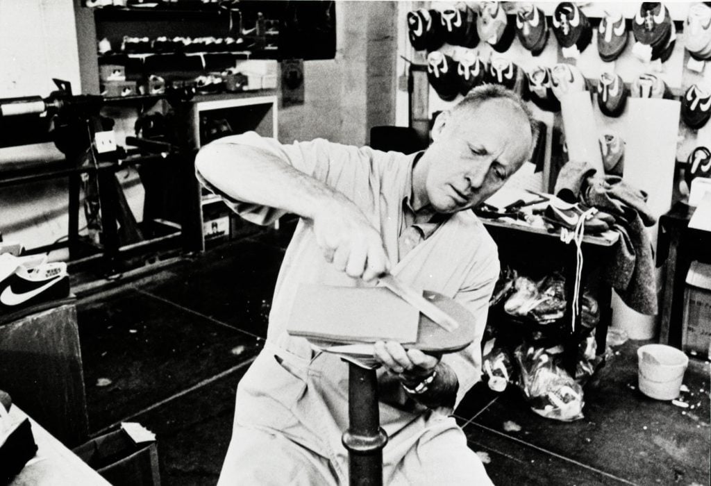 a man, Bill Bowerman, works on a shoe