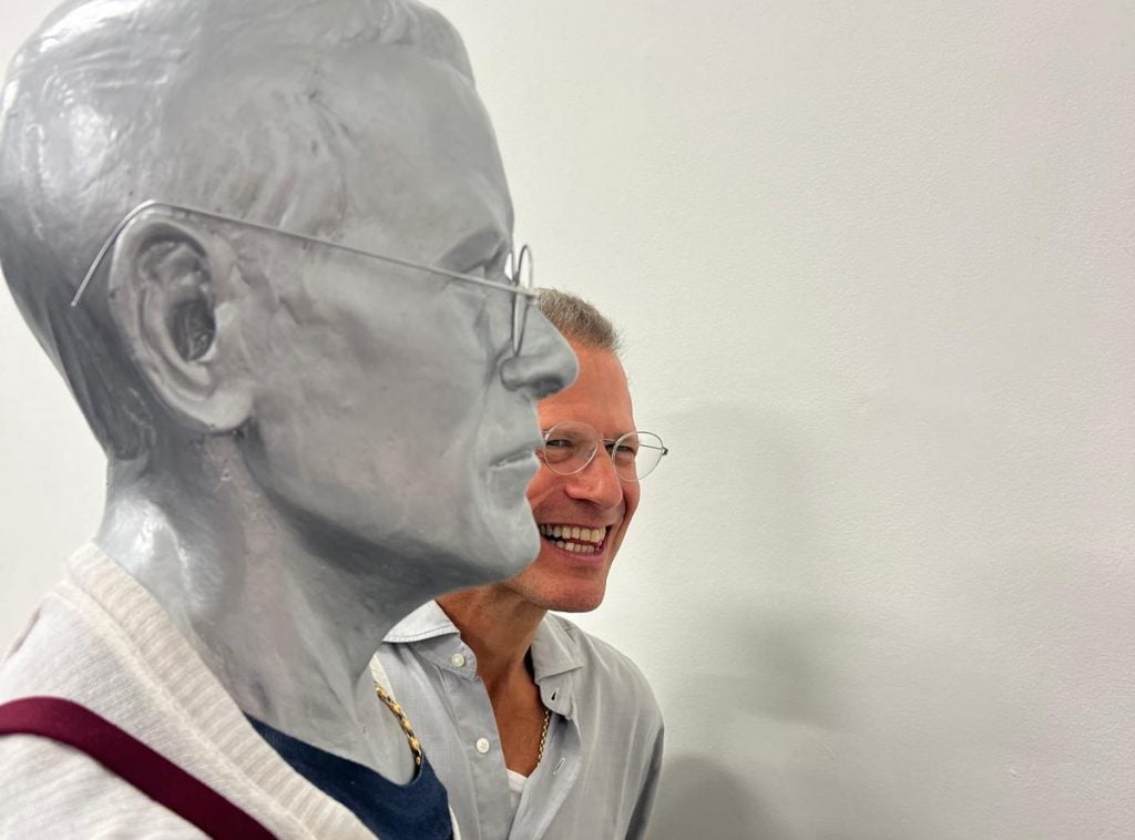 A man stands next to a sculpture of himself