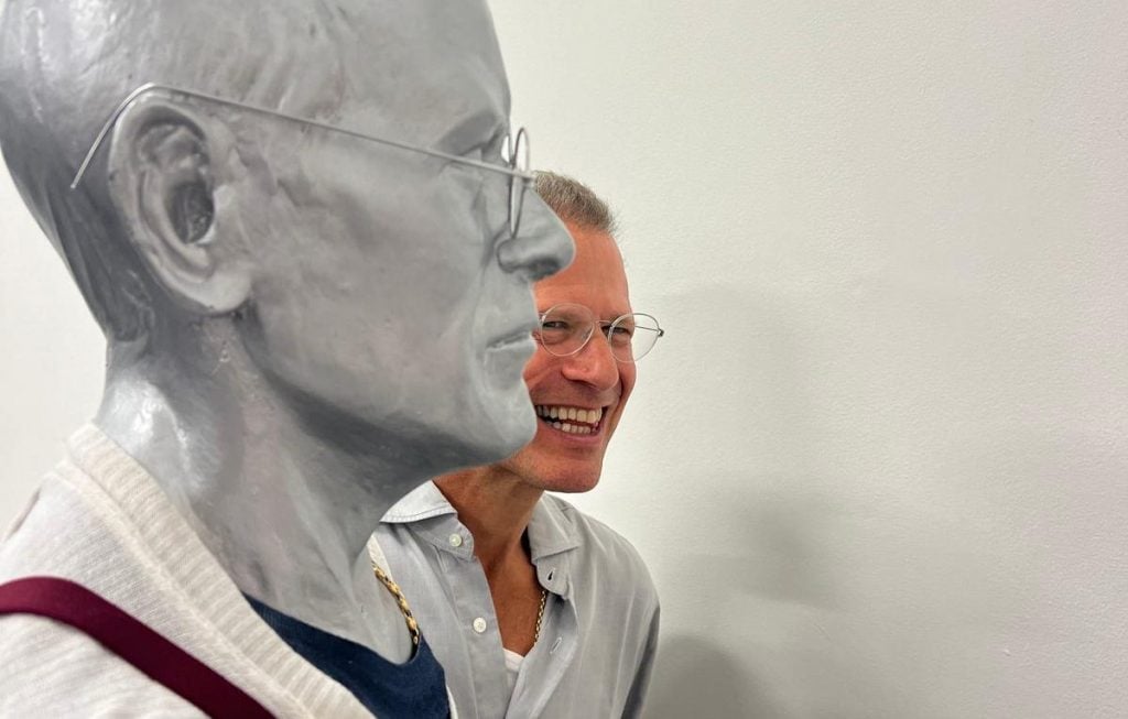 A man stands next to a sculpture of himself