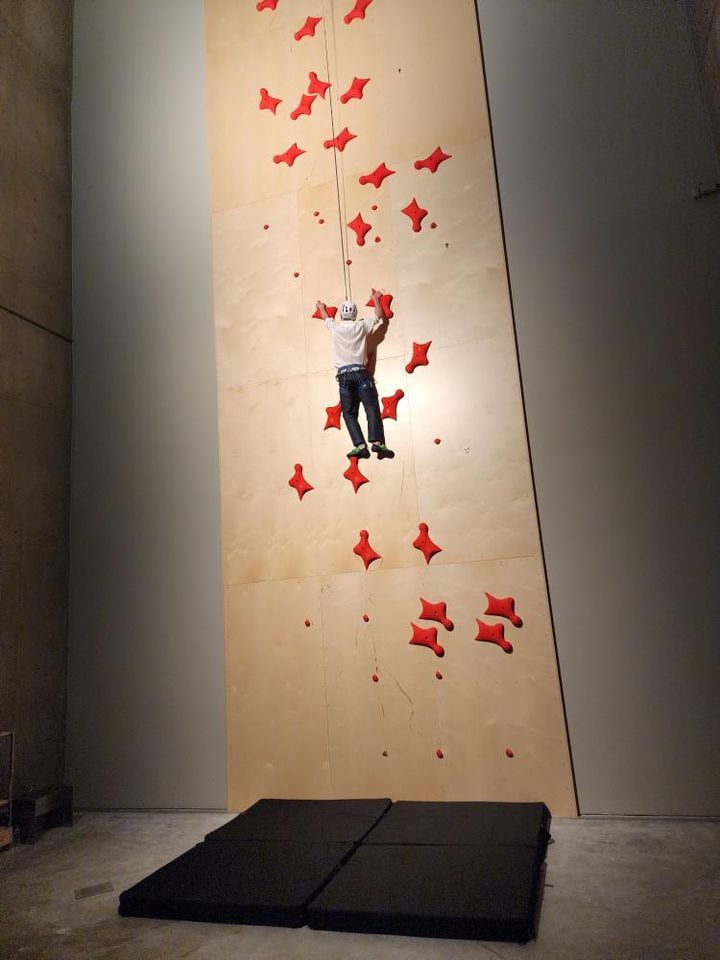 A man climbs a wall with a harness and rope