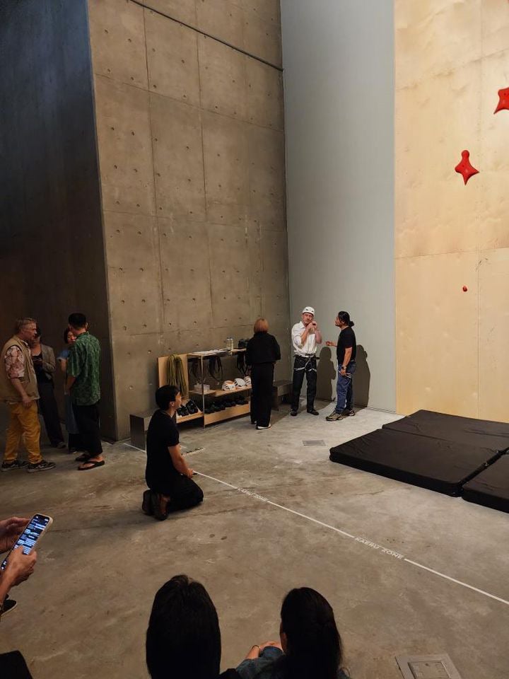 A man puts on a helmet next to a climbing wall