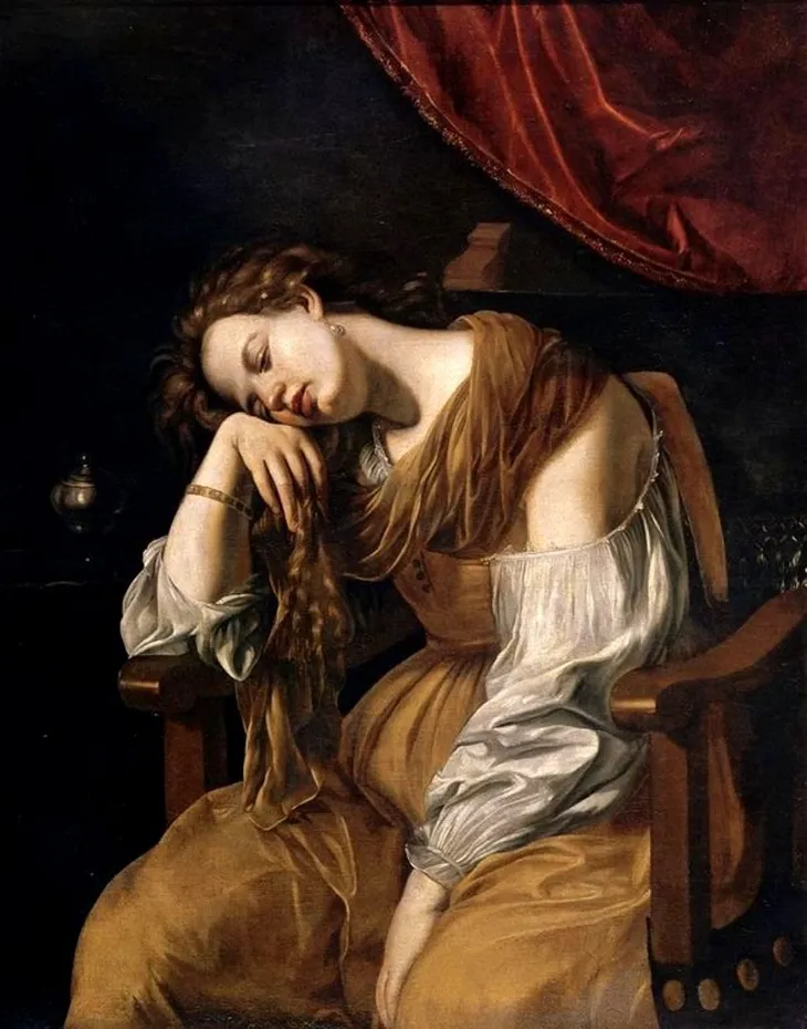 Penitent Mary Magdalene after Artemesia Gentileschi. The Baroque painting shows Mary Magdalene in a moment of contrition, renouncing her sinful life and the trappings of wealth and luxury to follow Jesus. She sits in a darkened room, her eyes closed as she rests her head on her hand. The painting is identifiable as a copy because of the out-of-place decorative wooden element above her shoulder—the copyist misidentified a tassel in the original work.