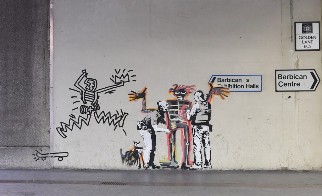 The Barbican placed a protective sheeting over a mural by street artist Banksy of his version of a work by the late Jean-Michel Basquiat, created on the occasion of the late artist's 2017 solo show at the London museum. Artist Danny Minnick then added his own drawing to the piece, titled Banksquiat. Boy and Dog in Stop and Search, which shows two stenciled police officer figures frisking Basquiat's skeletal figure. 