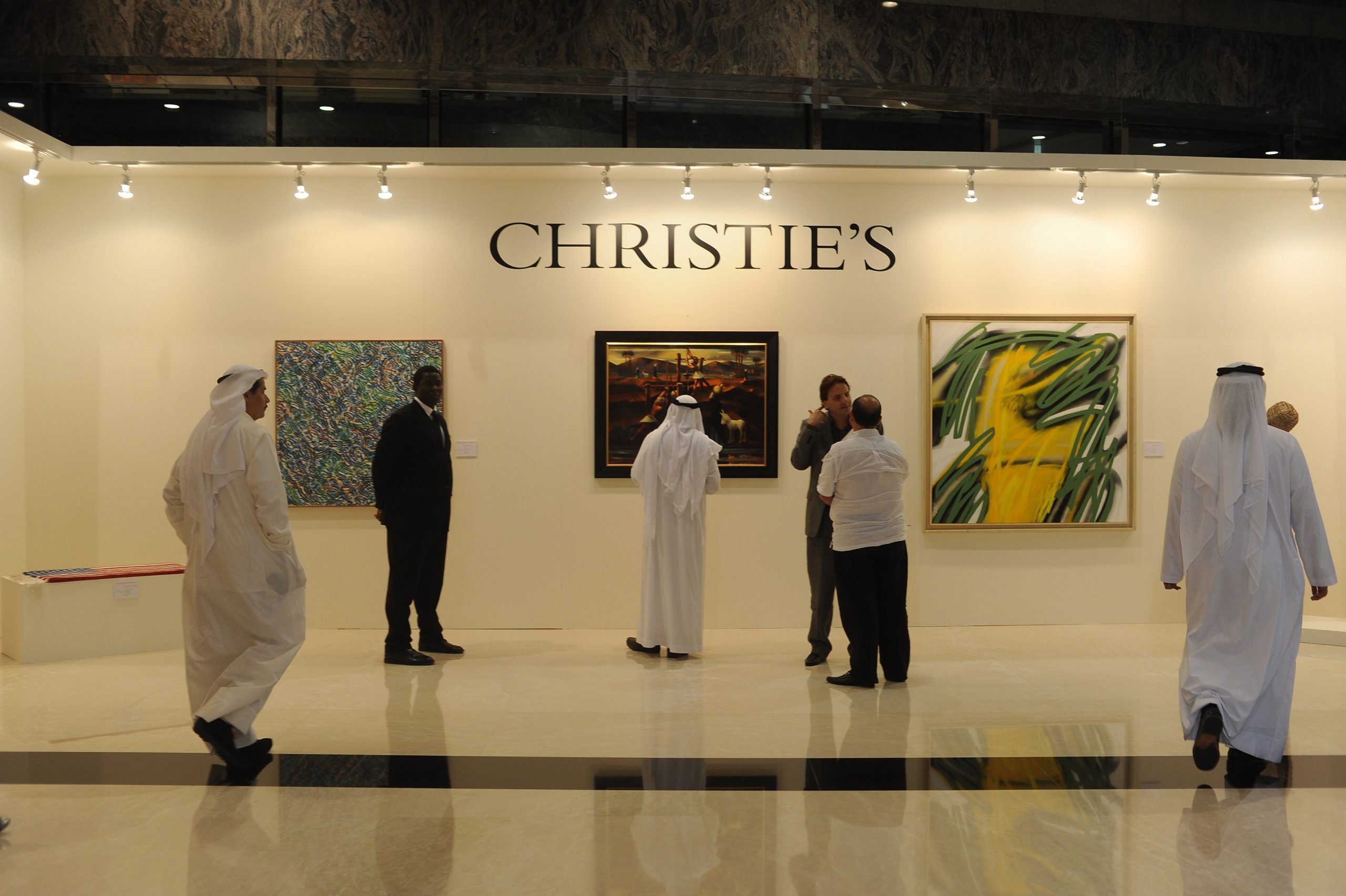 An Emirati man in white dish-dasha looks at a painting by an Egyptian artist at Christie's Dubai