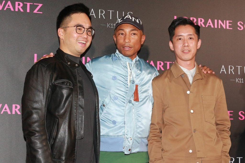 three men pose for a picture in front of an event backdrop