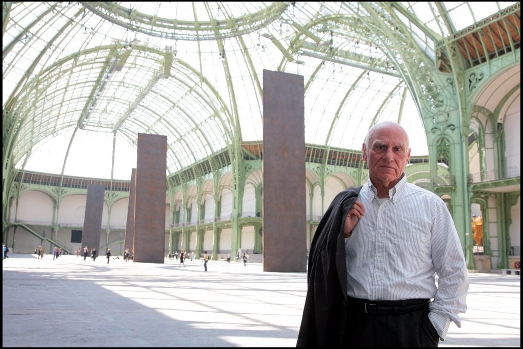 the sculptor Richard serra stands in the grand Palis in front of his sculptures 