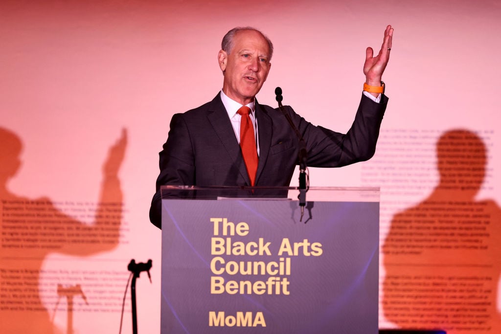 A man in a suit speaks at a podium