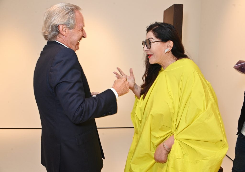 A man speaks animatedly to a woman in a yellow dress