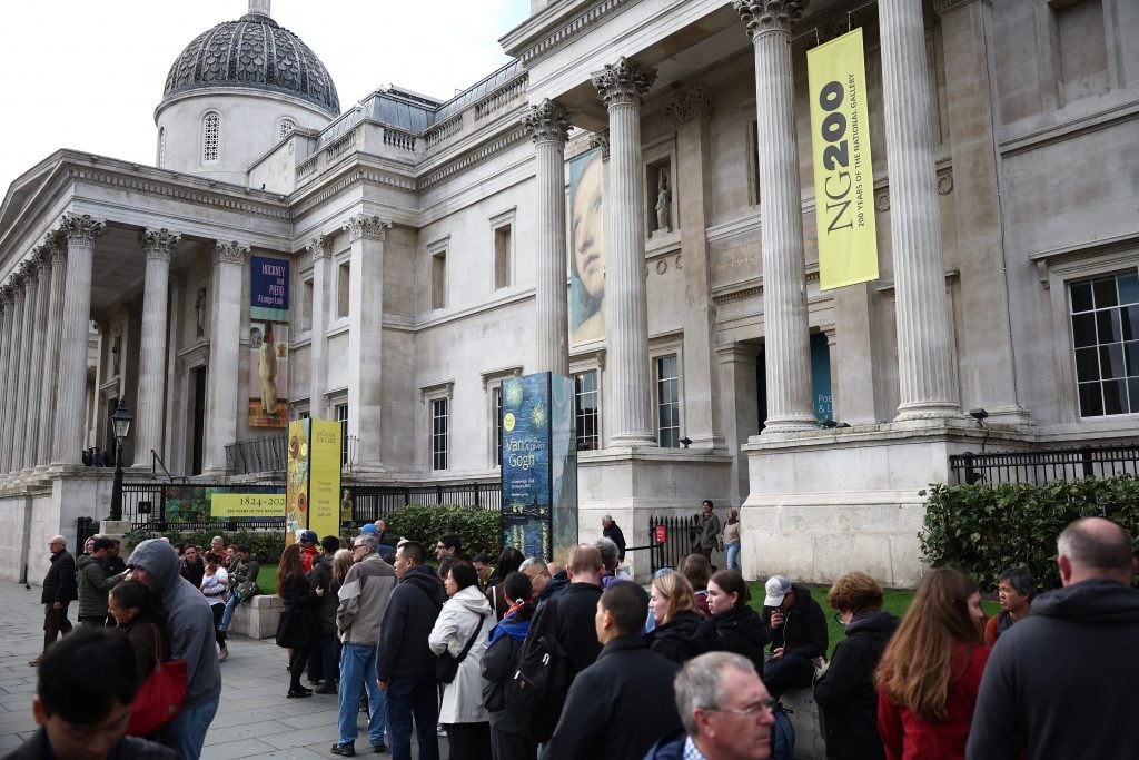 a line of people outside of a large neoclassical building with pillars