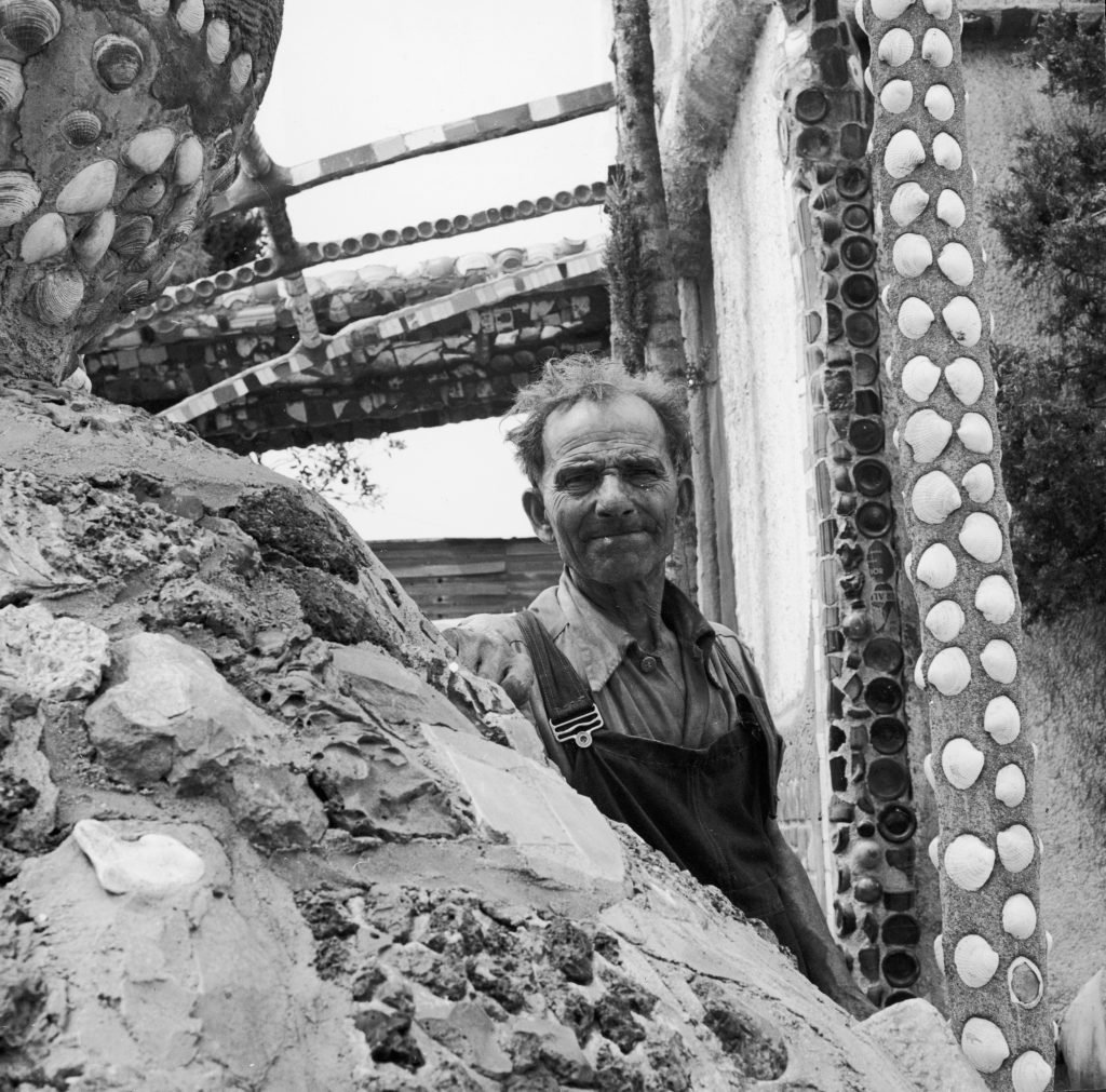 an old man in overalls is standing in his construction the watts towers 