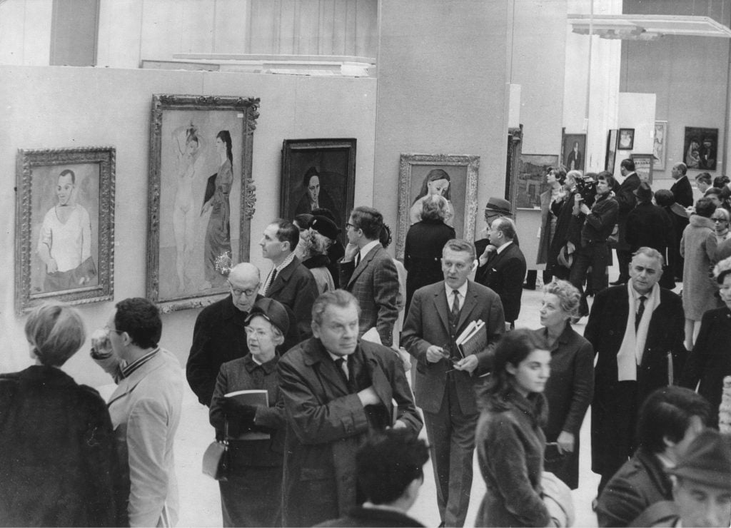 a throng of attendees are viewing a Picasso exhibit in a gallery hall