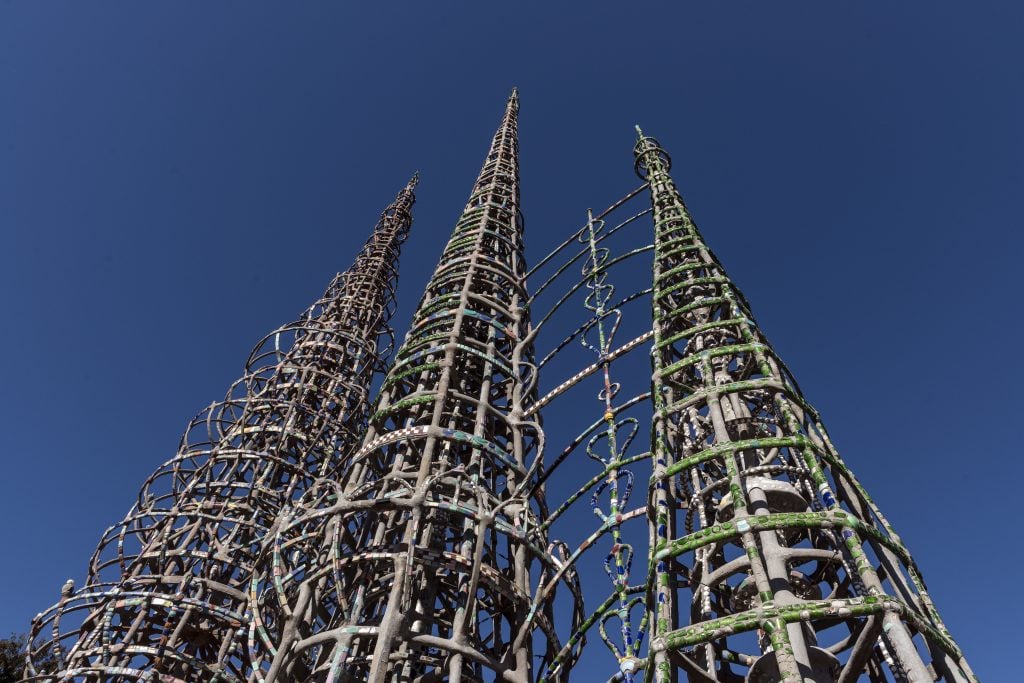 Three towering, spiraled metal structures of the Watts Towers against a clear blue sky