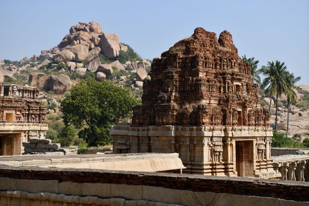 A temple at Hampi, India in the foreground with a hill of boulders in the back