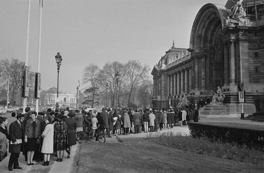 a very large line of people are waiting to get into the grand Palais in Paris 