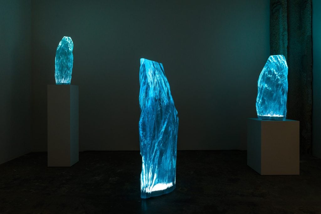 a darkened gallery highlights sculptural lamps that look like ice fragments 