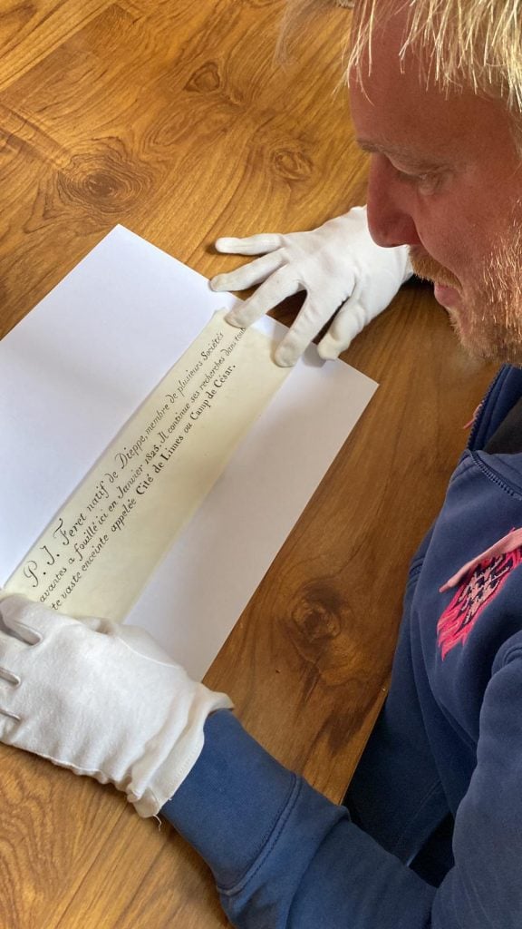 a man reads an unscrolled note on a wooden table