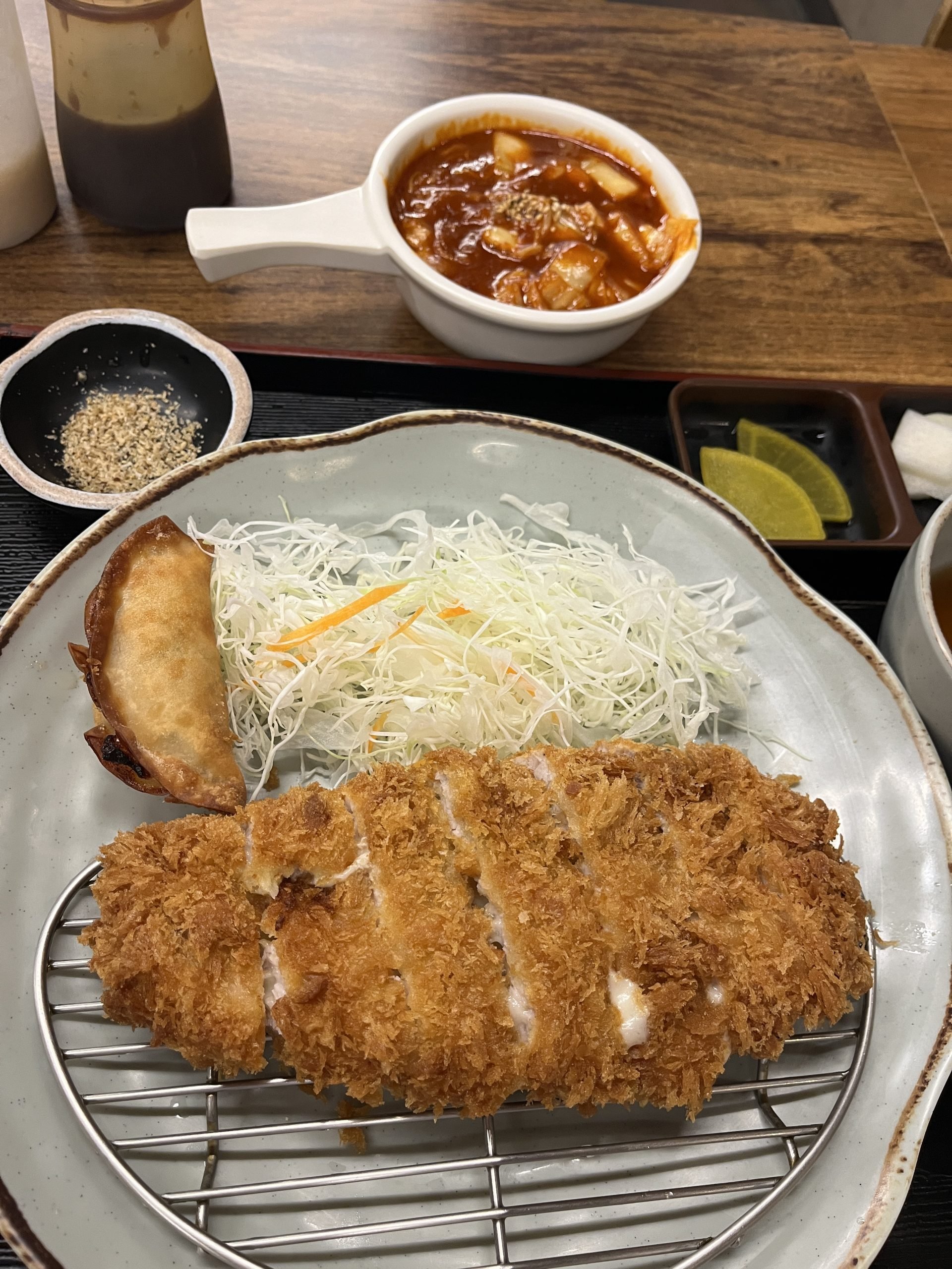 A breaded, fried cutlet sits on a wire platform next to shredded cabbage. Delicious!