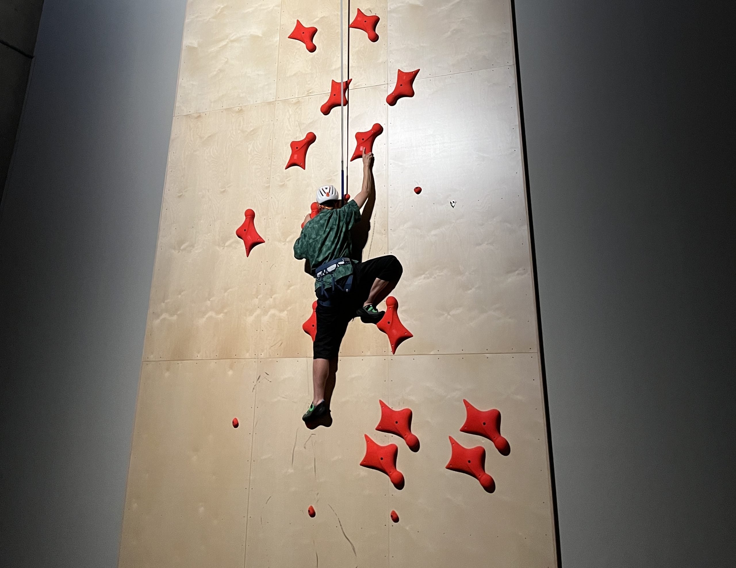 A man tries to climb a wall in a color photo