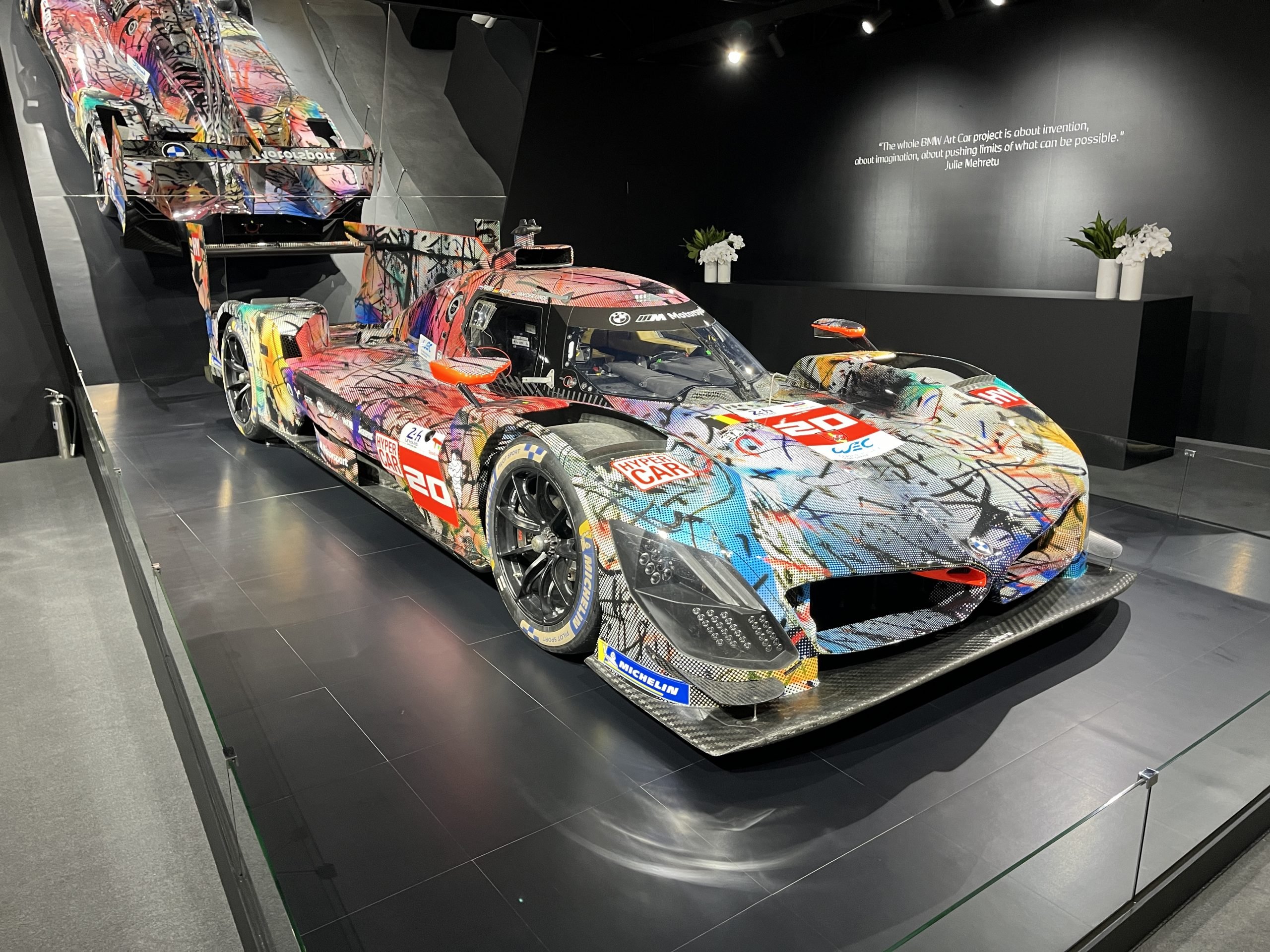 A black-walled booth holds an aerodynamic-looking racecar emblazoned with all sorts of wild images.