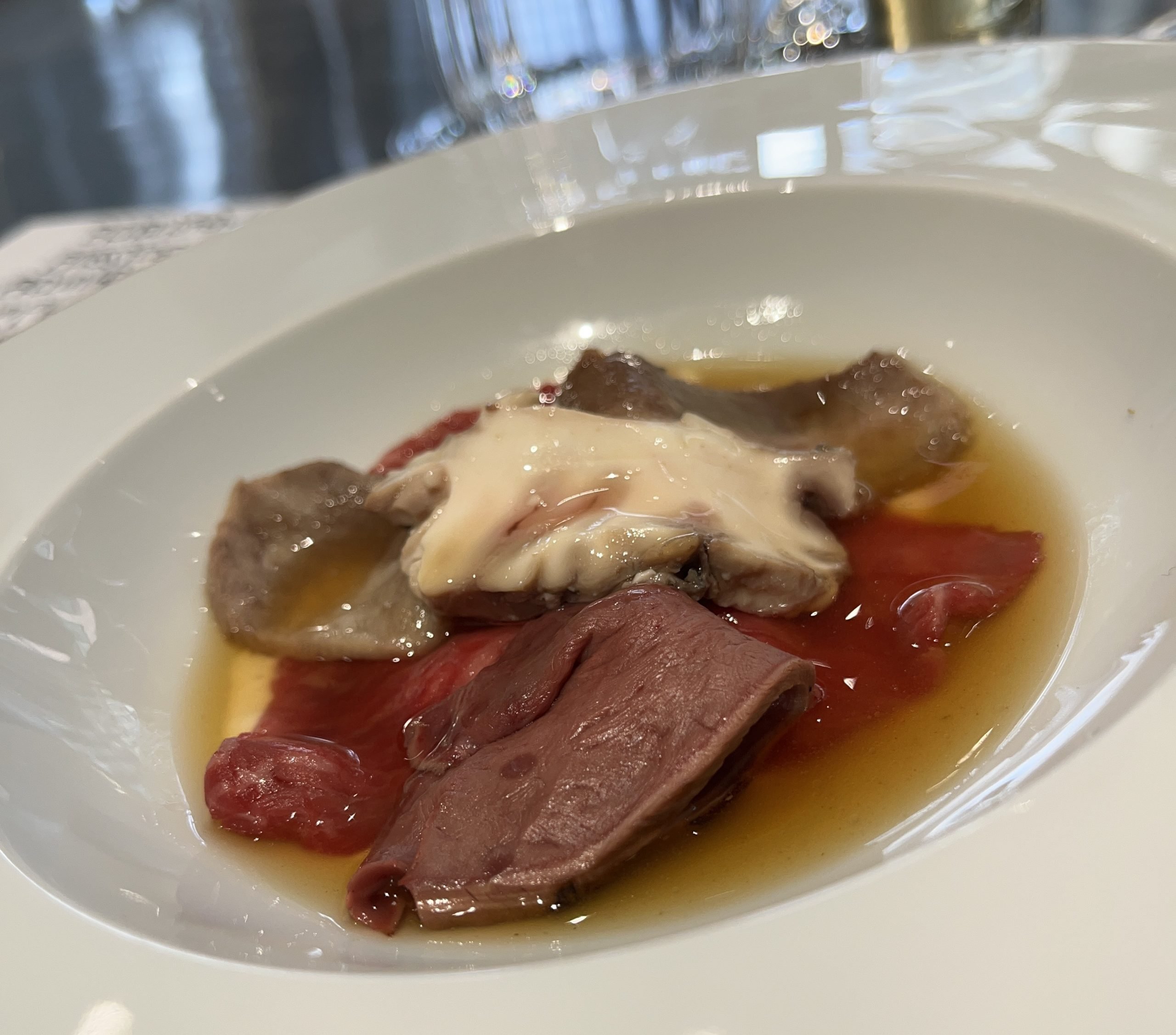 A variety of pieces of red meat sit in a bowl.