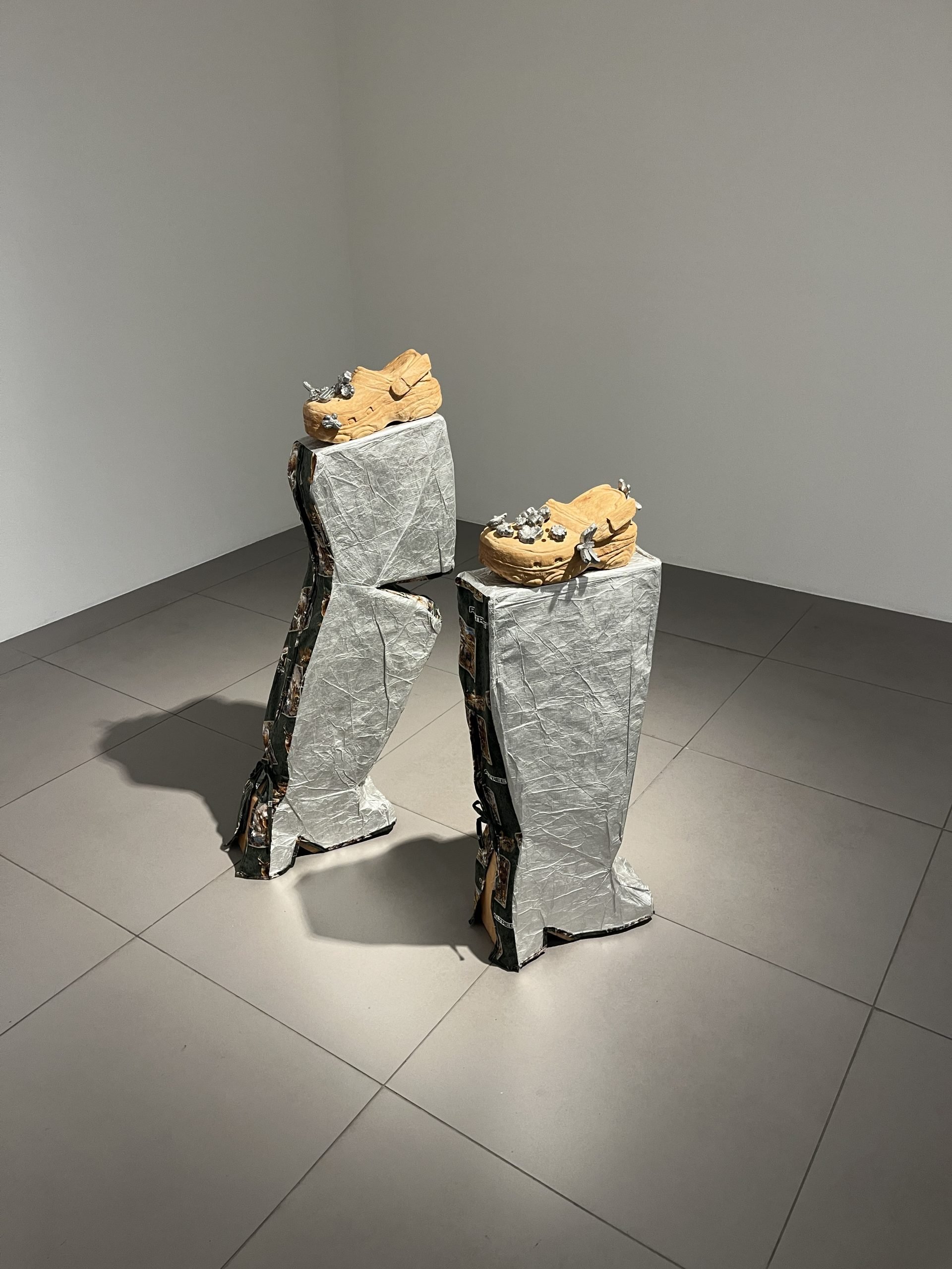 Two wooden Crocs sit atop two gray-silver booths on a gray floor.