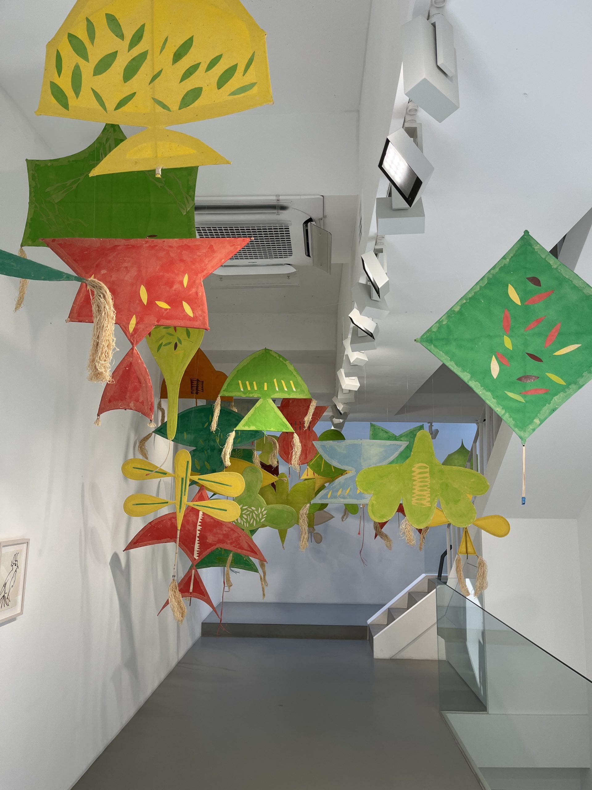 Kites Yellow, green, and red kites hang near the ceiling of a white-walled space.