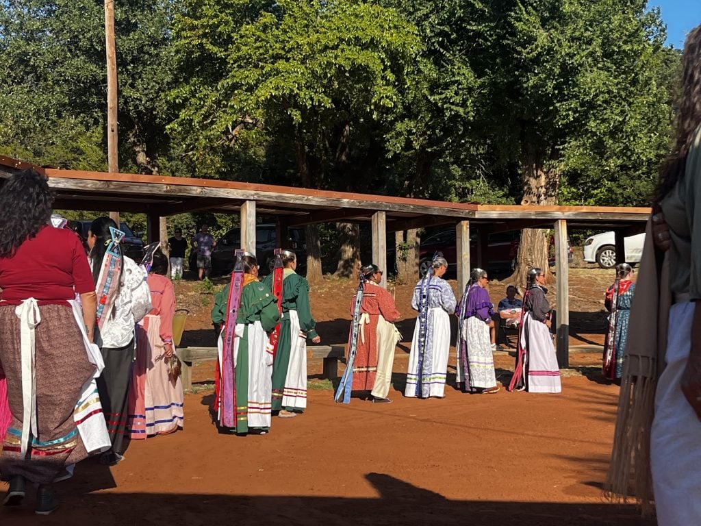 indigenous women in ceremonial dress form a line