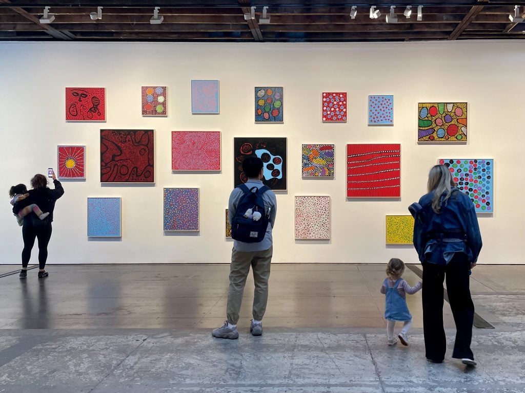 Exhibition goers and their children admiring the paintings on the wall