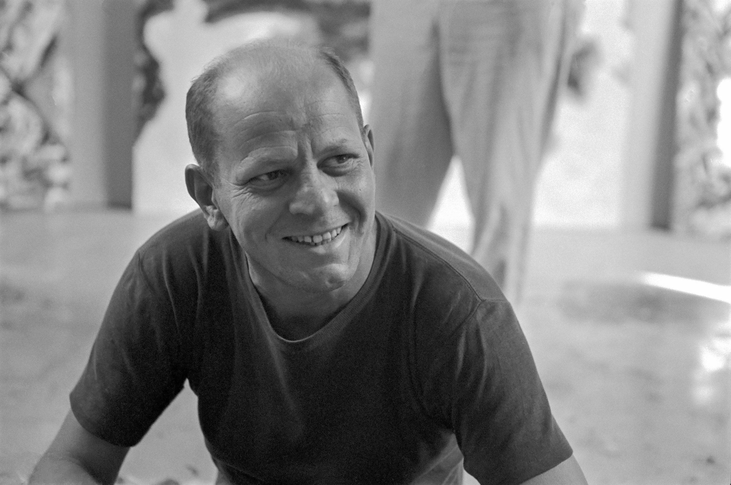 a black and white photo of a man in a tee shirt identified as artist jackson pollock