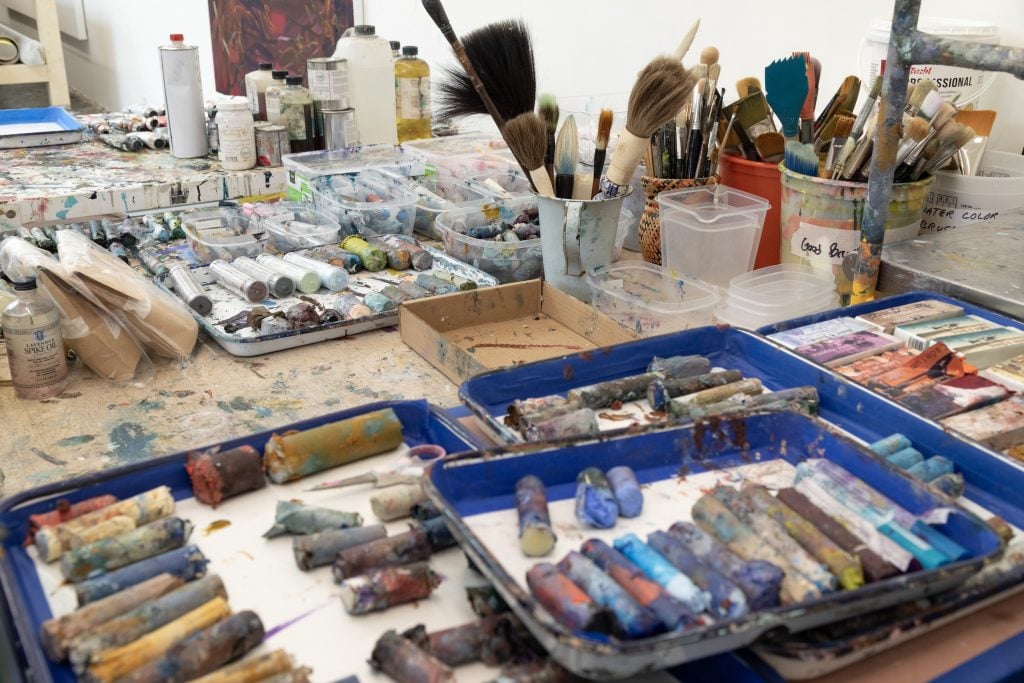 pastels on a table near brushes in an artist studio