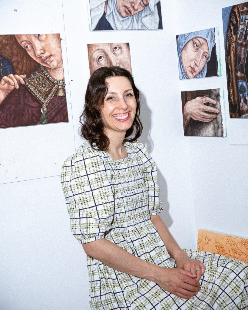 a woman in a prairie style dress sits in front of paintings