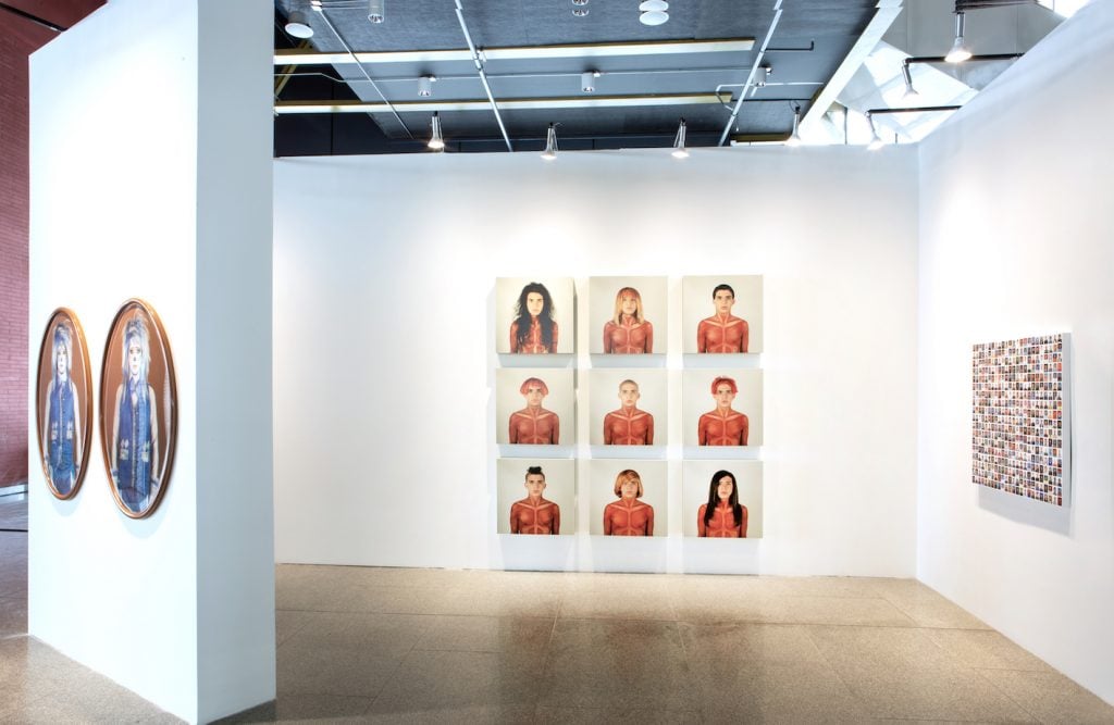 an art fair booth is installed with self-portraits of an artist in various guises 