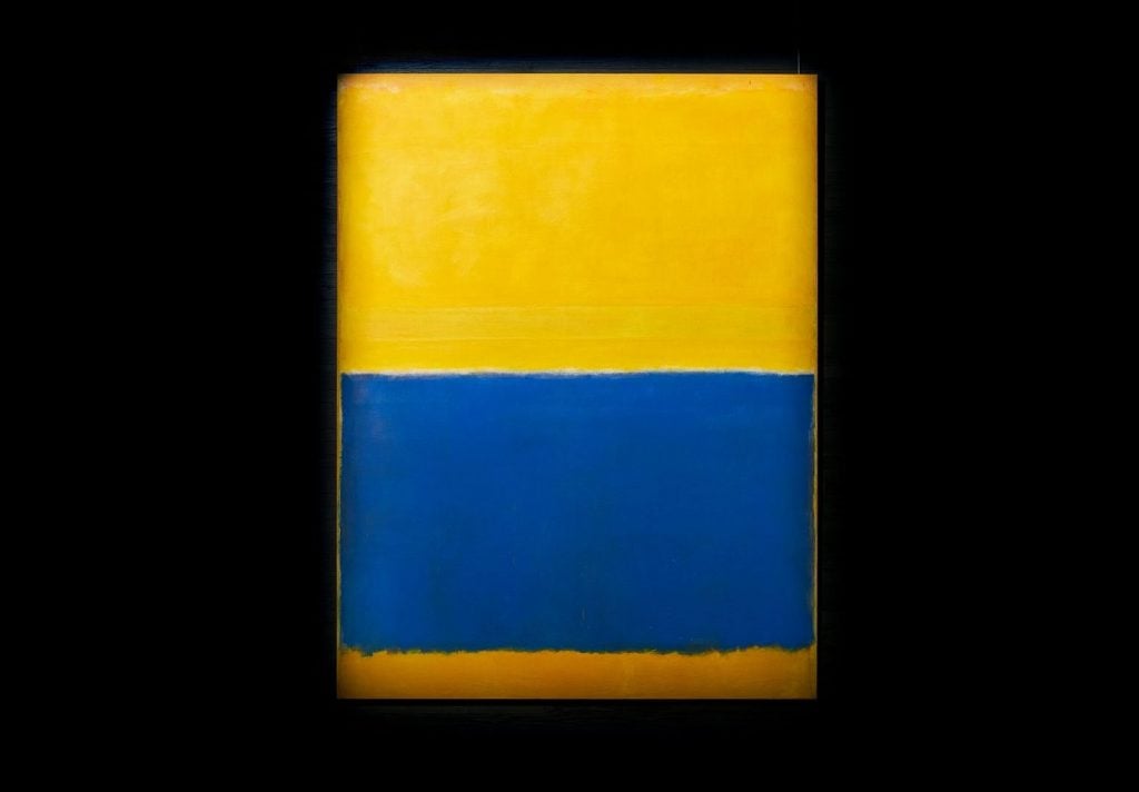 a blue and yellow painting on a black wall