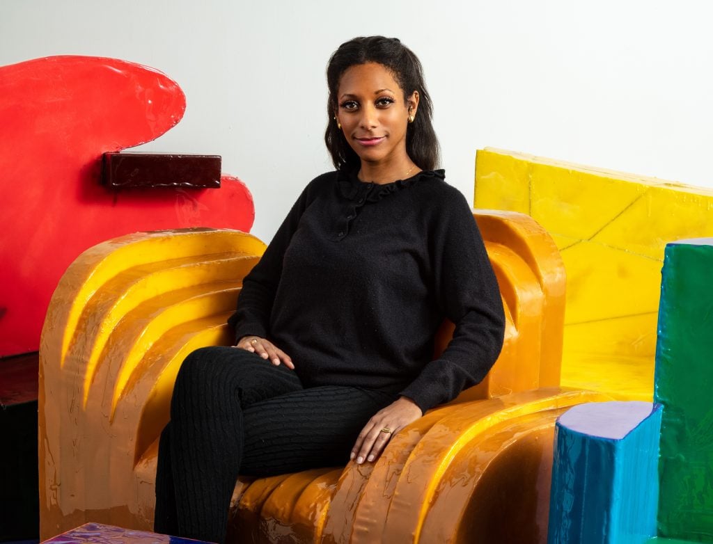 the designer Luam Melake is wearing all black and seated on her colorful furniture