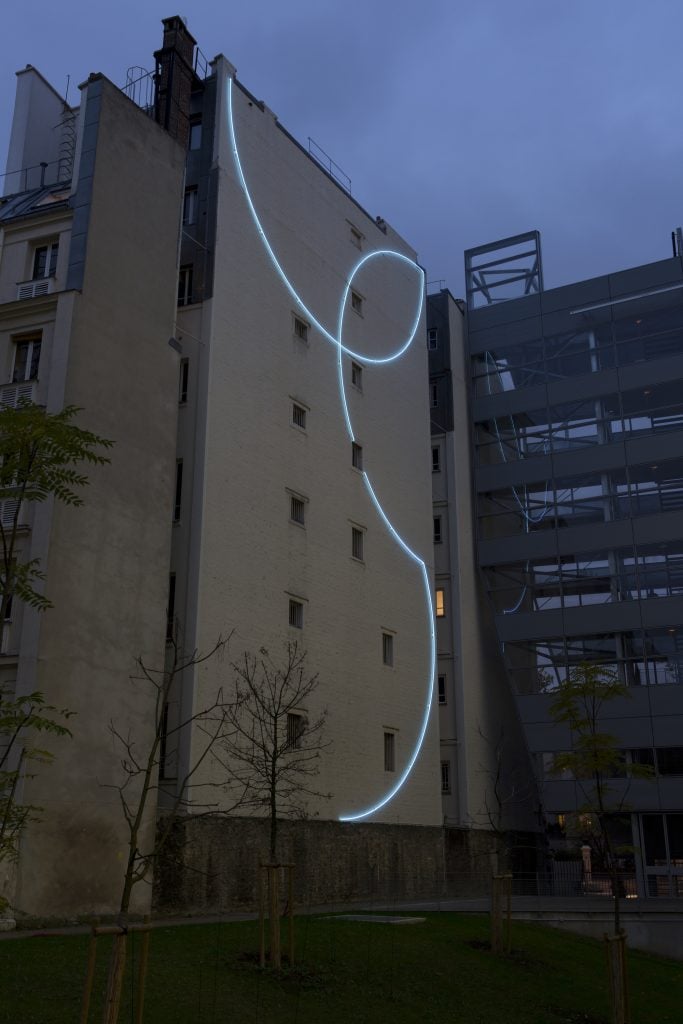 an image of a blue neon artwork installed on the side of Institu Imagine in Paris