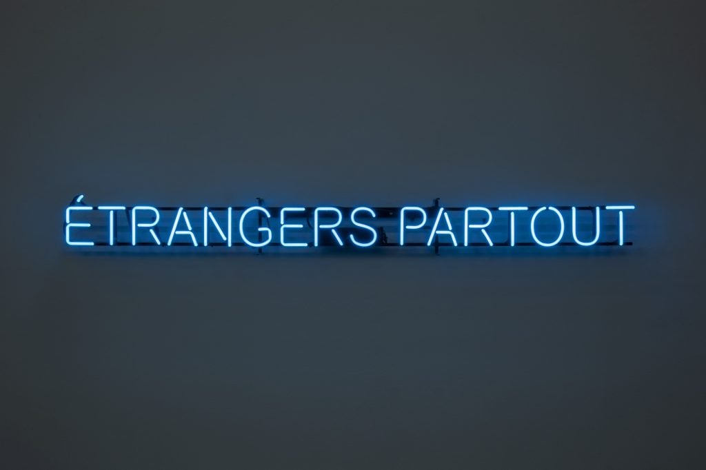 an image of a neon sign that reads Etrangers Partout