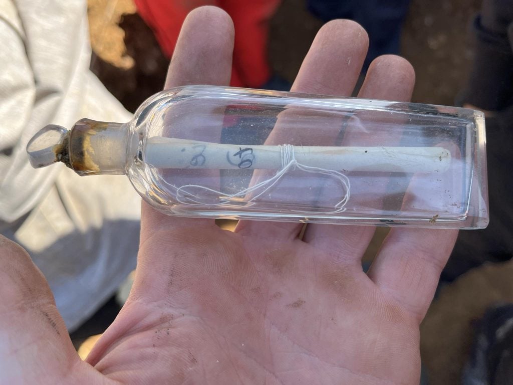 a close up of a hand holding a vial with a note rolled up inside