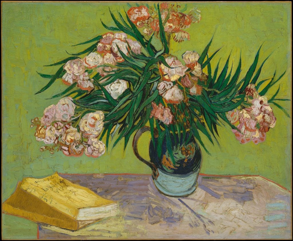 a painting of a vase of pinky white flowers with long leaves on a table against a green wall, there is also a book with a yellow cover on the table