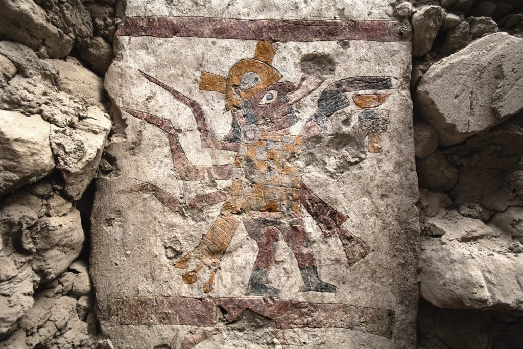 Ancient carving of a human body with spider features carrying a goblet