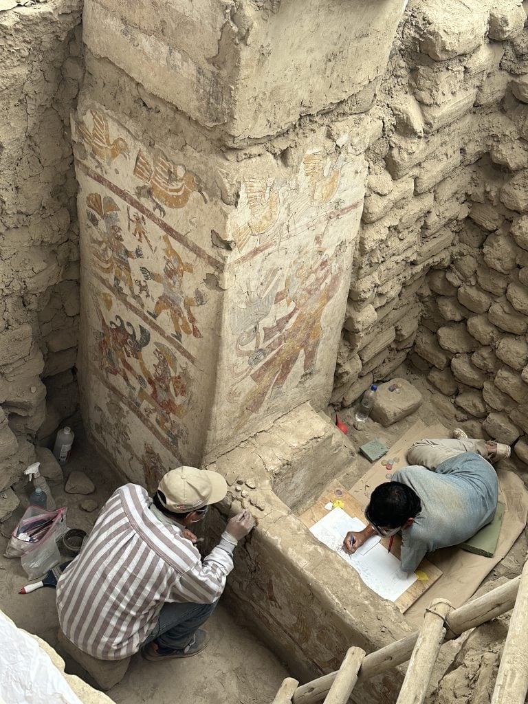 two people work on restoring an old wall