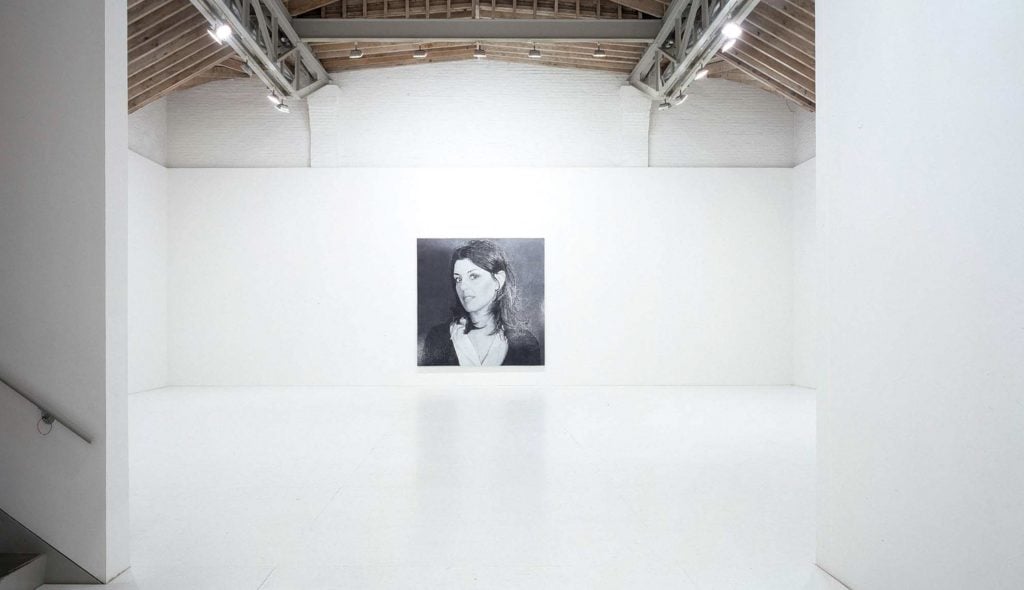 a black and white portrait of an attractive white woman displayed in a huge gallery space