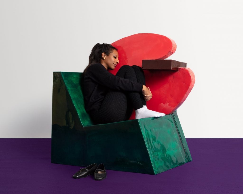 the designer is clad in black and is atop a colorful chair