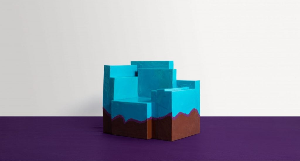 a boxy blue and brown polyurethane chair is atop valet carpet in a gallery 