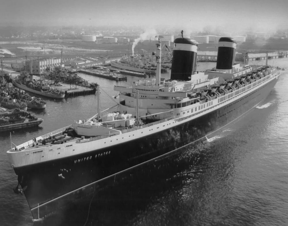 A black and white photo of the SS United States, a huge ocean liner, departing Norfolk Naval Shipyard in 1952.