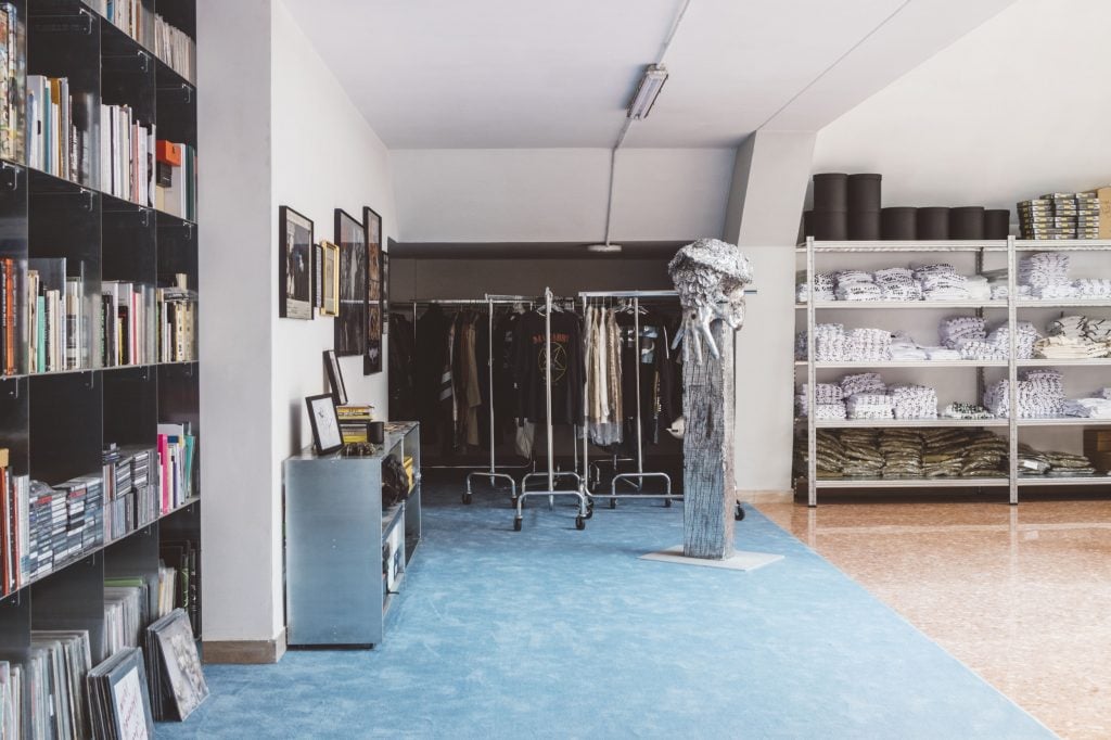 an interior space lined with book shelves, racks of clothes, shelves and framed photographs