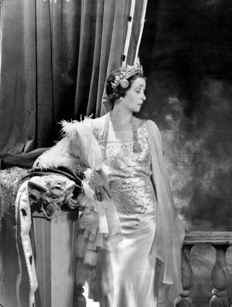 a woman stands in a black and white photograph wearing diamond necklace