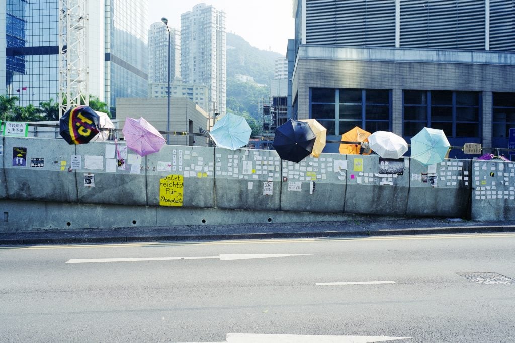 Colourful umbrellas danging on the railing of a highway.