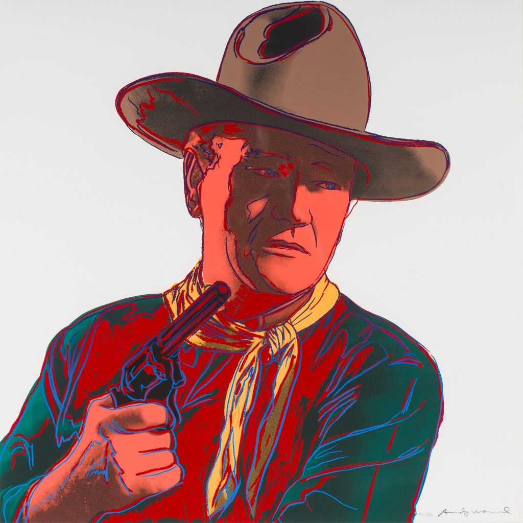 A sillkscreen print by Andy Warhol showing John Wayne wearing a cowboy hat and holding a revolver, from his cowboys and Indians series.